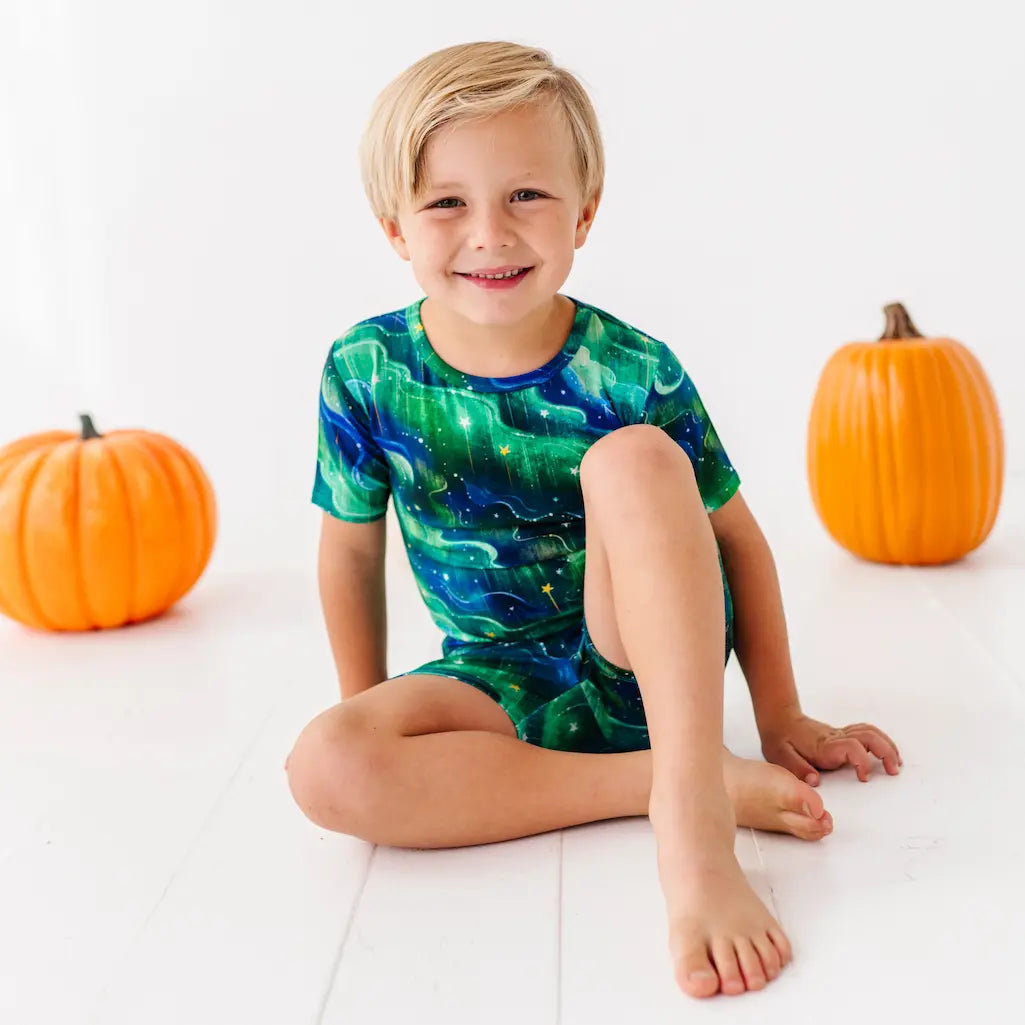 Child wearing a green and blue northern lights patterned outfit on a white background