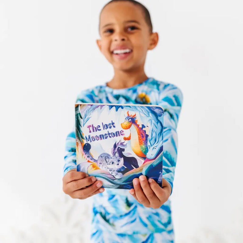 Child holding a book titled 'The Lost Moonstone' with a white background