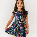 Young girl wearing a colorful dress with floral and moon designs on a white background