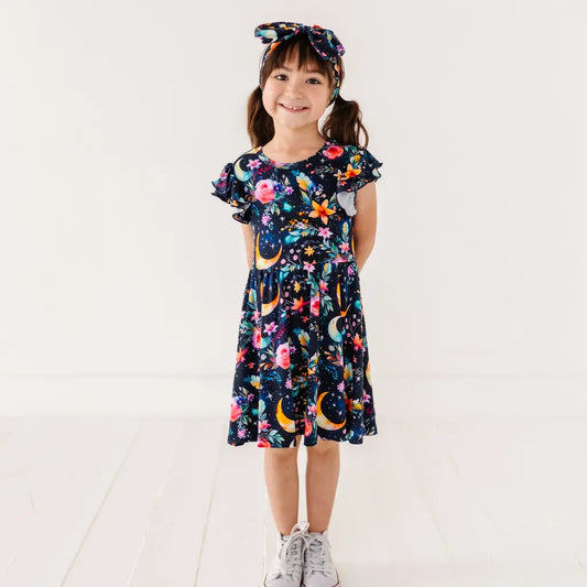 Young girl wearing a colorful floral dress with a white background