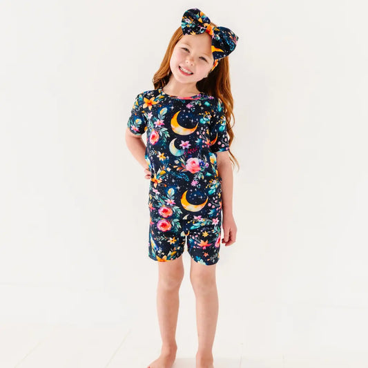Child wearing a colorful nightgown with floral and moon designs on a white background