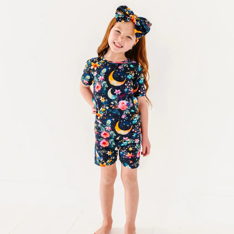 Child wearing a colorful nightgown with floral and moon designs on a white background