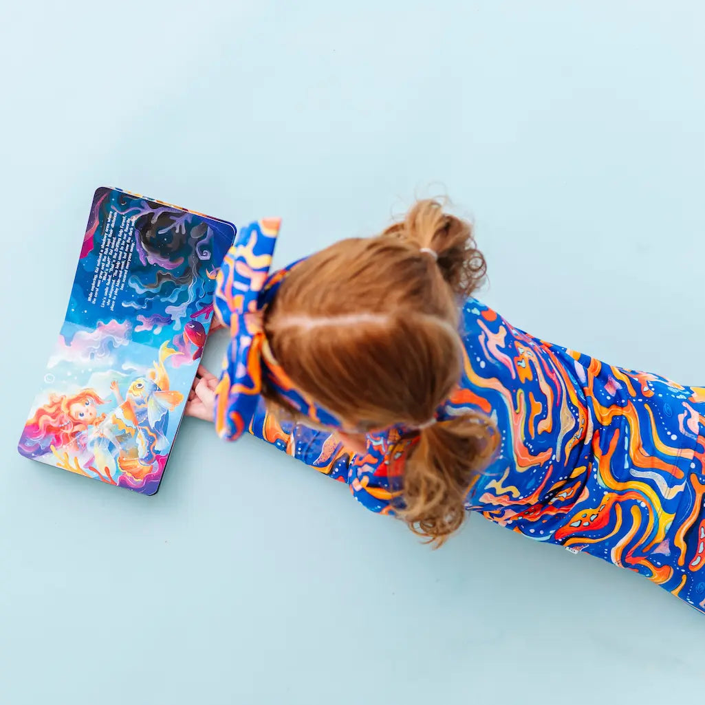Person lying on a colorful abstract-patterned mat with a phone beside them on a light blue background.