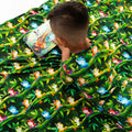 Child reading a book on a green fabric with colorful frog pattern