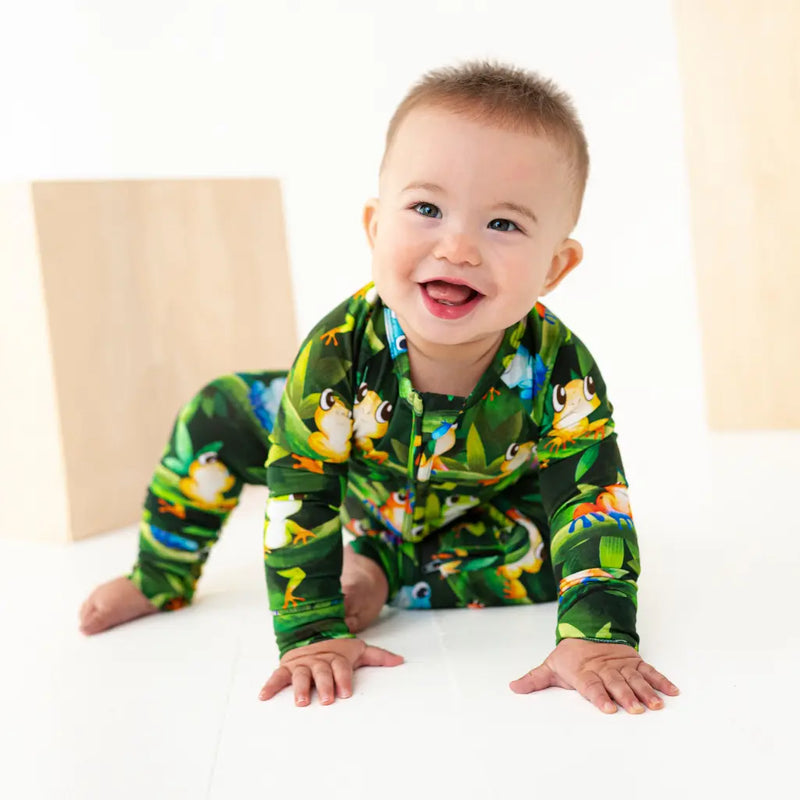 Baby wearing a colorful frog-themed onesie on a white background