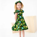 Young girl wearing a green dress with animal print on a white background