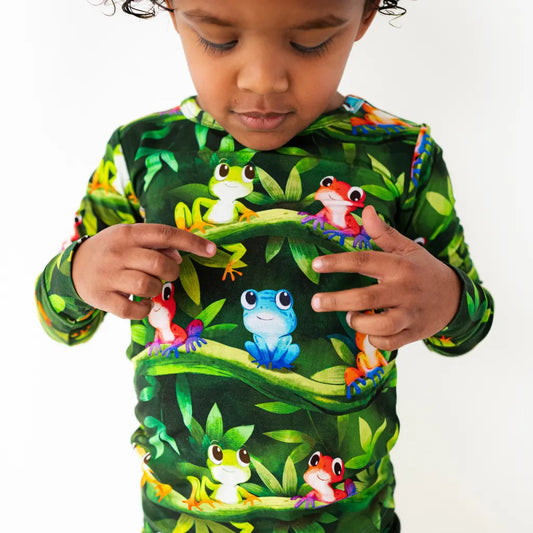 Child wearing a colorful frog-themed shirt on a white background