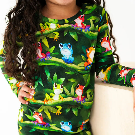 Child wearing a shirt with colorful frog design on a green background