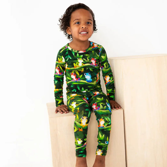 Child wearing a green pajama set with animal prints on a white background