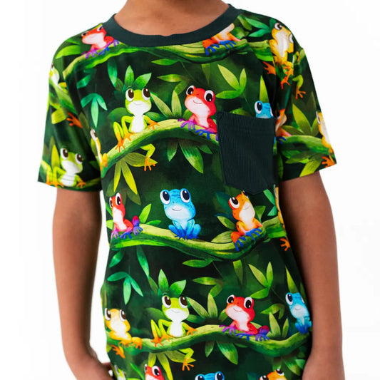 Child wearing a t-shirt with colorful frog pattern on a green background