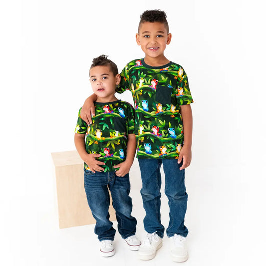 Two children wearing matching green t-shirts with animal prints on a white background