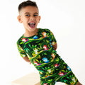 Child wearing a green pajama set with frog pattern on a white background