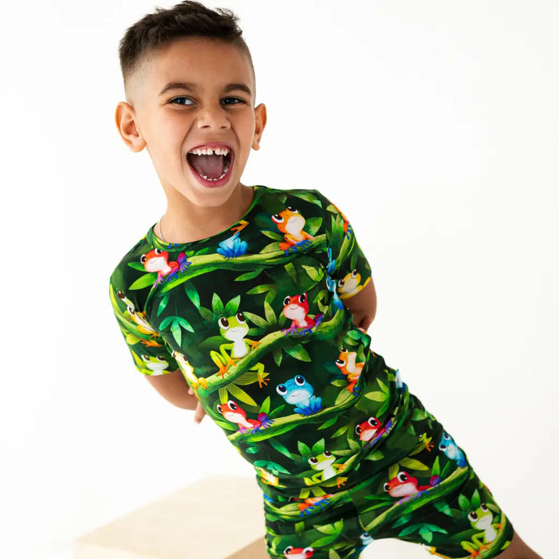 Child wearing a green pajama set with frog pattern on a white background
