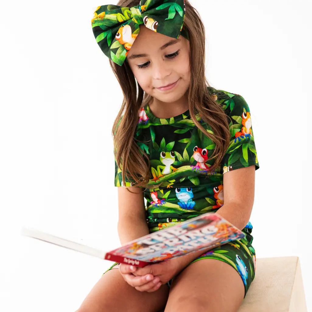 Young girl wearing a jungle-themed outfit with a matching headband, sitting on a white background.