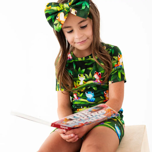 Young girl wearing a jungle-themed outfit with a matching headband, sitting on a white background.
