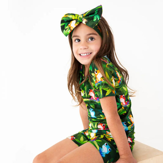 Young girl wearing a green animal-themed outfit with a matching headband on a white background