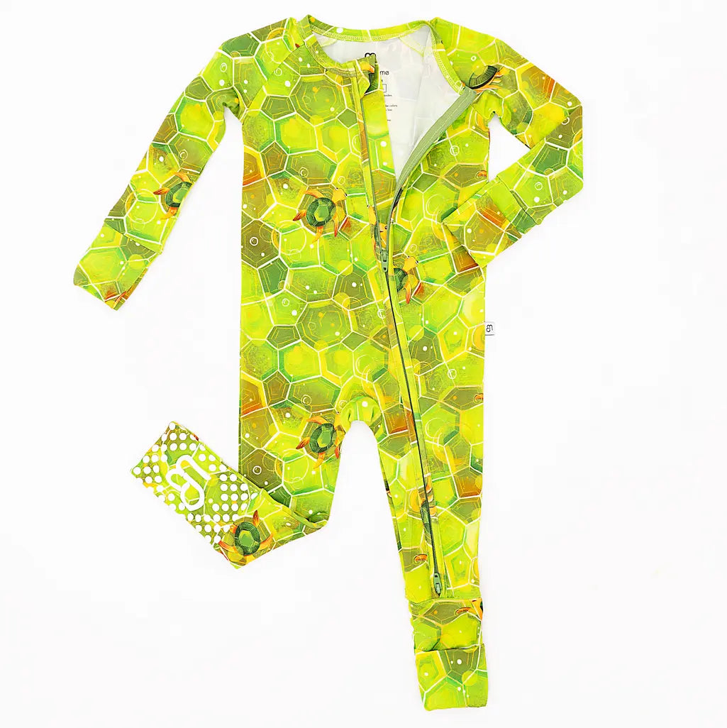 One-piece zipper pajama with geometric green shell patterns and hexagonal turtle designs, intended for baby wear.