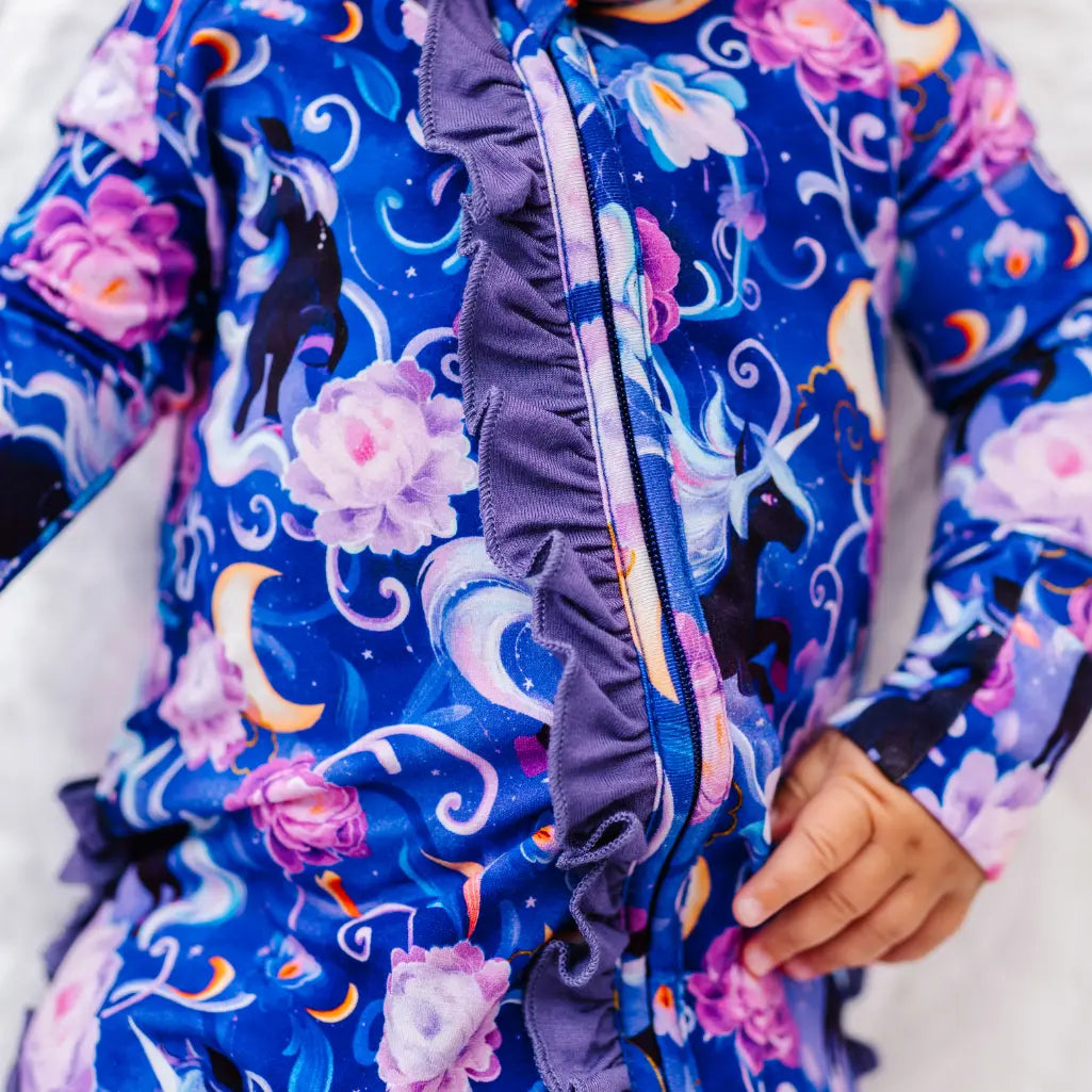 Close-up of a child's colorful floral and unicorn patterned jacket with a hand visible.