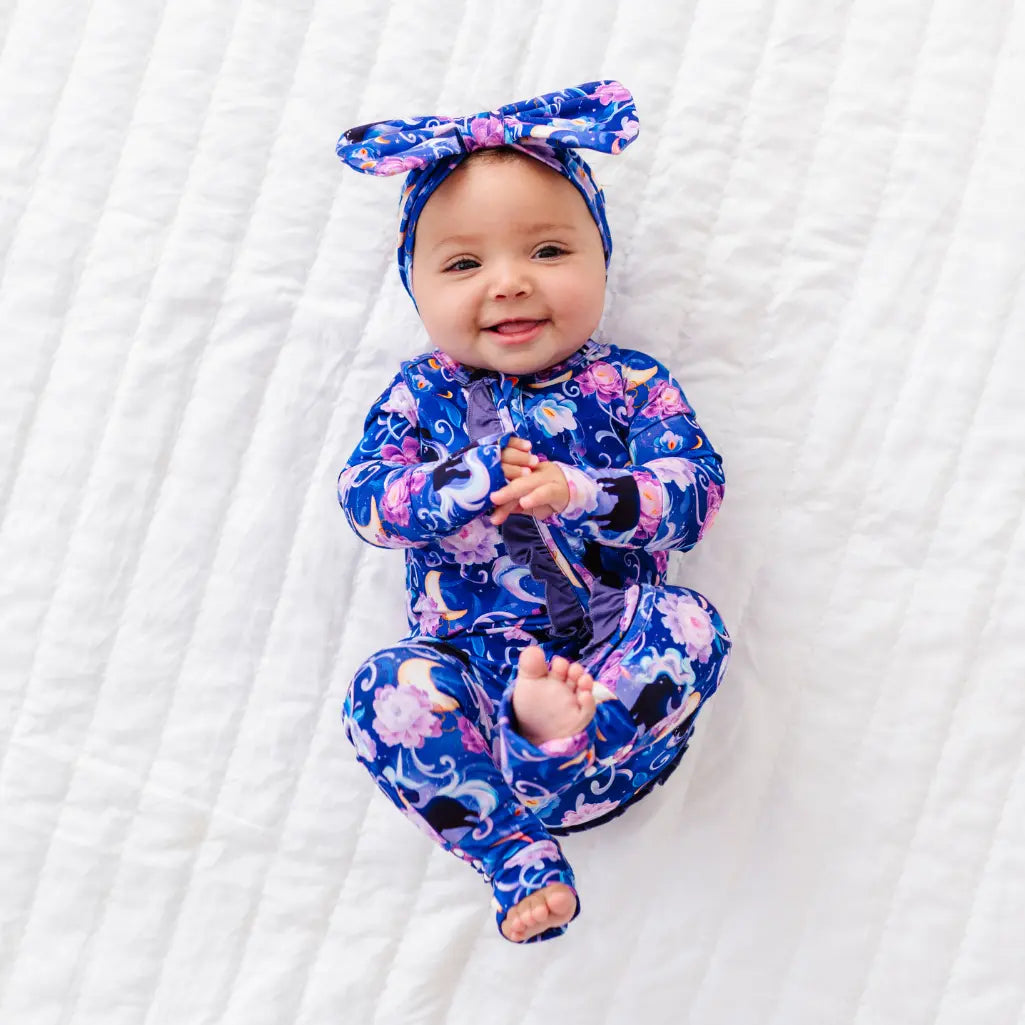 Baby wearing a blue floral outfit with a matching headband on a white background