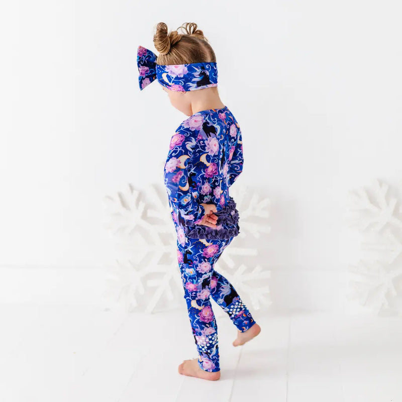 Child wearing a colorful outfit with a floral and animal pattern on a white background