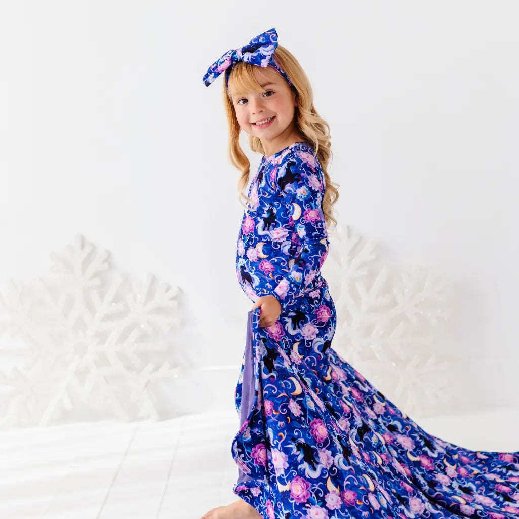 Young girl wearing a blue floral dress with a matching headband on a white background