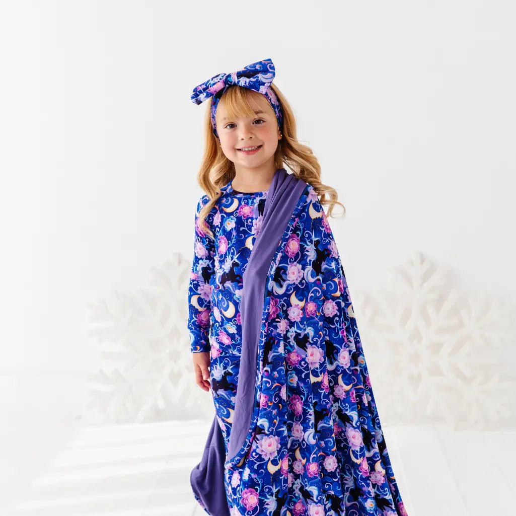 Young girl wearing a floral dress with a purple scarf and headband on a white background
