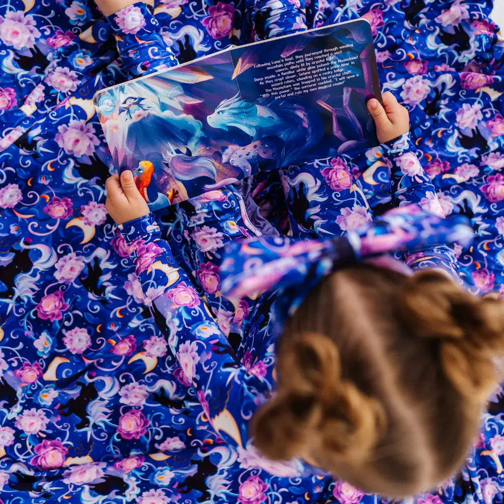 Child reading a book with a colorful unicorn pattern on a matching blanket