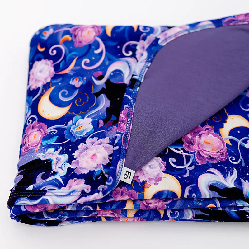 Folded blanket with a colorful floral and moon design on a white background