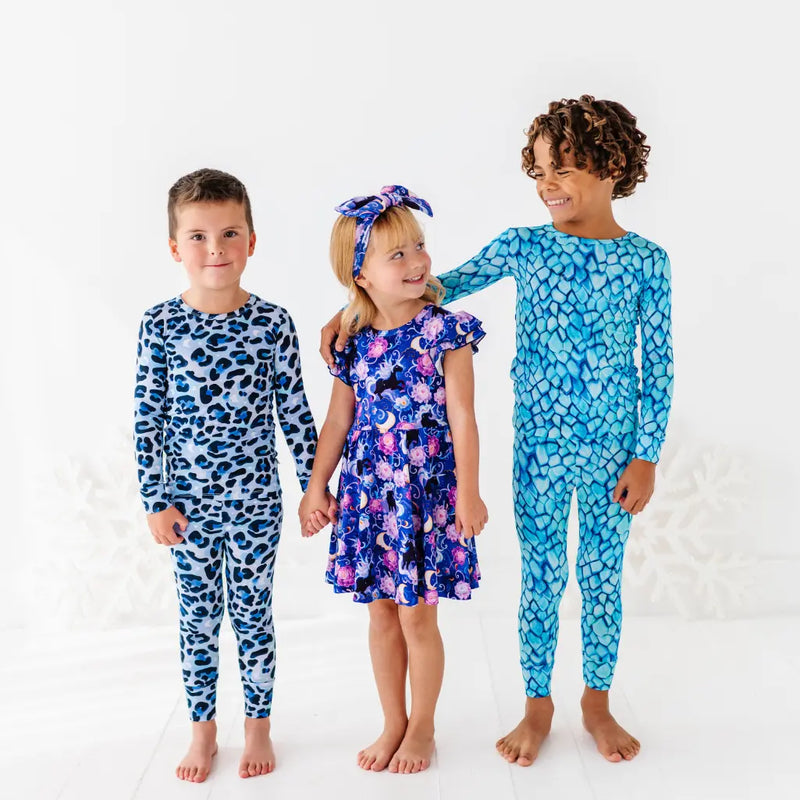 Three children wearing blue patterned pajamas on a white background