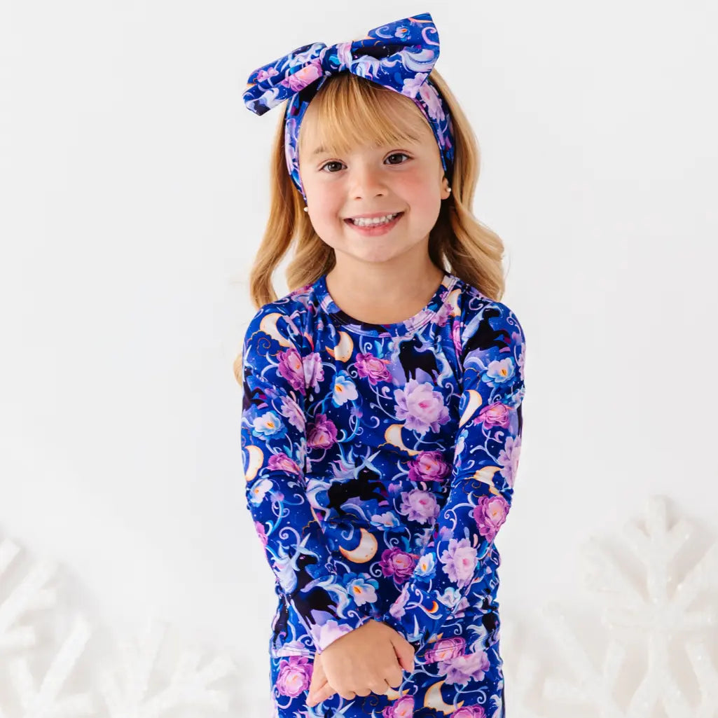 Child wearing a blue floral outfit with a matching headband on a white background