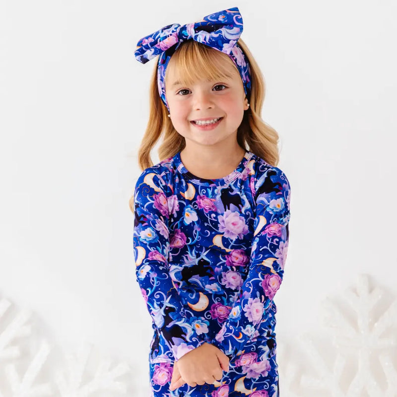 Child wearing a blue floral outfit with a matching headband on a white background