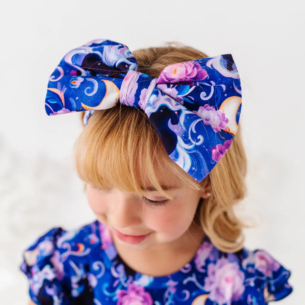 Child wearing a large, colorful headband with a blue and purple pattern on a white background