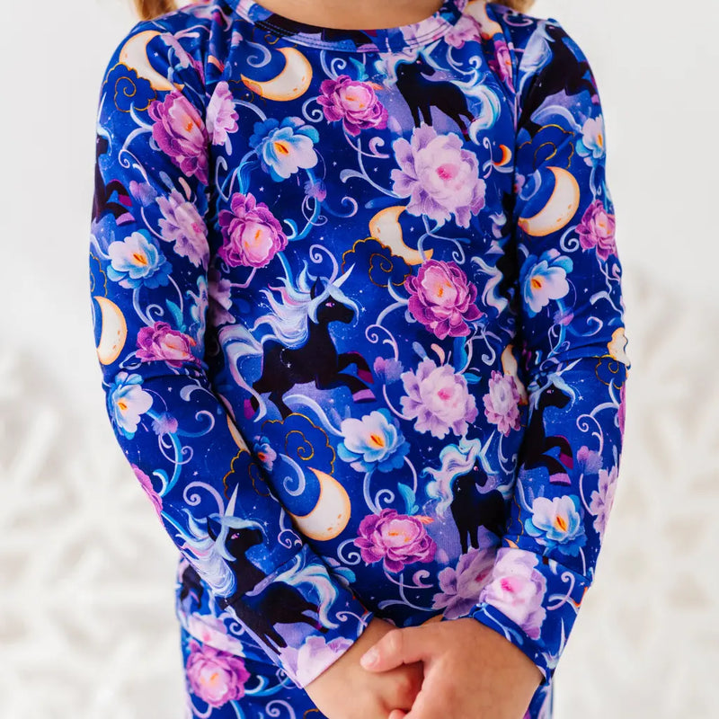 Child wearing a long-sleeve shirt with a unicorn and floral pattern on a white background