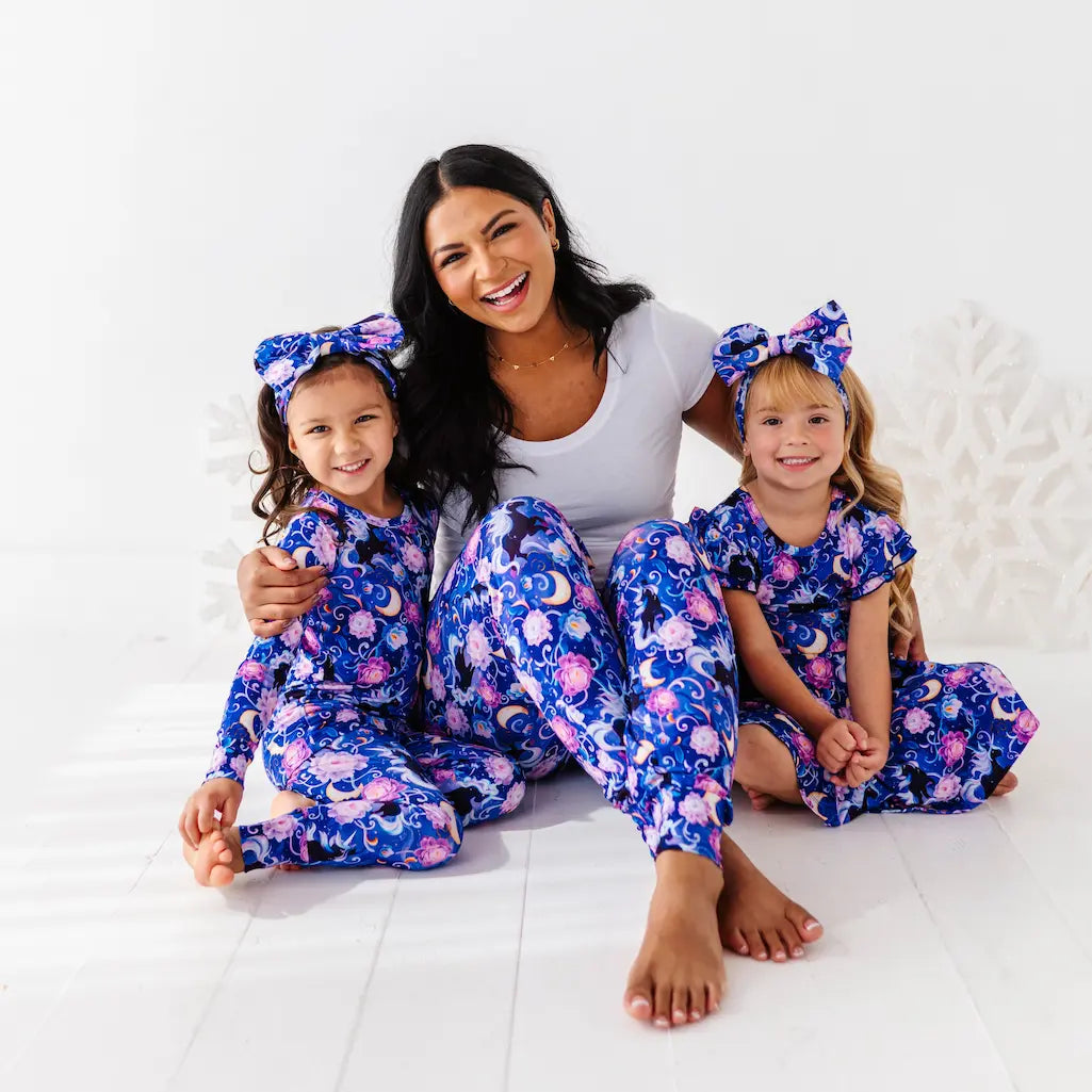 Woman and two children wearing matching blue floral pajamas on a white background