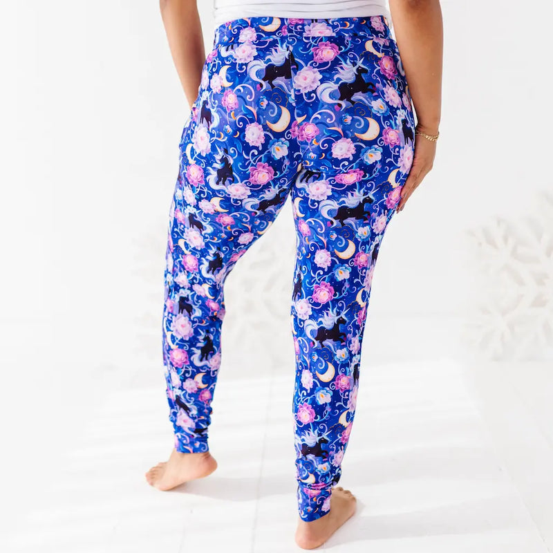 Person wearing blue leggings with cat and moon pattern on a white background