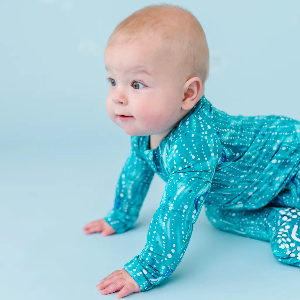 Baby in blue polka dot outfit on a light blue background