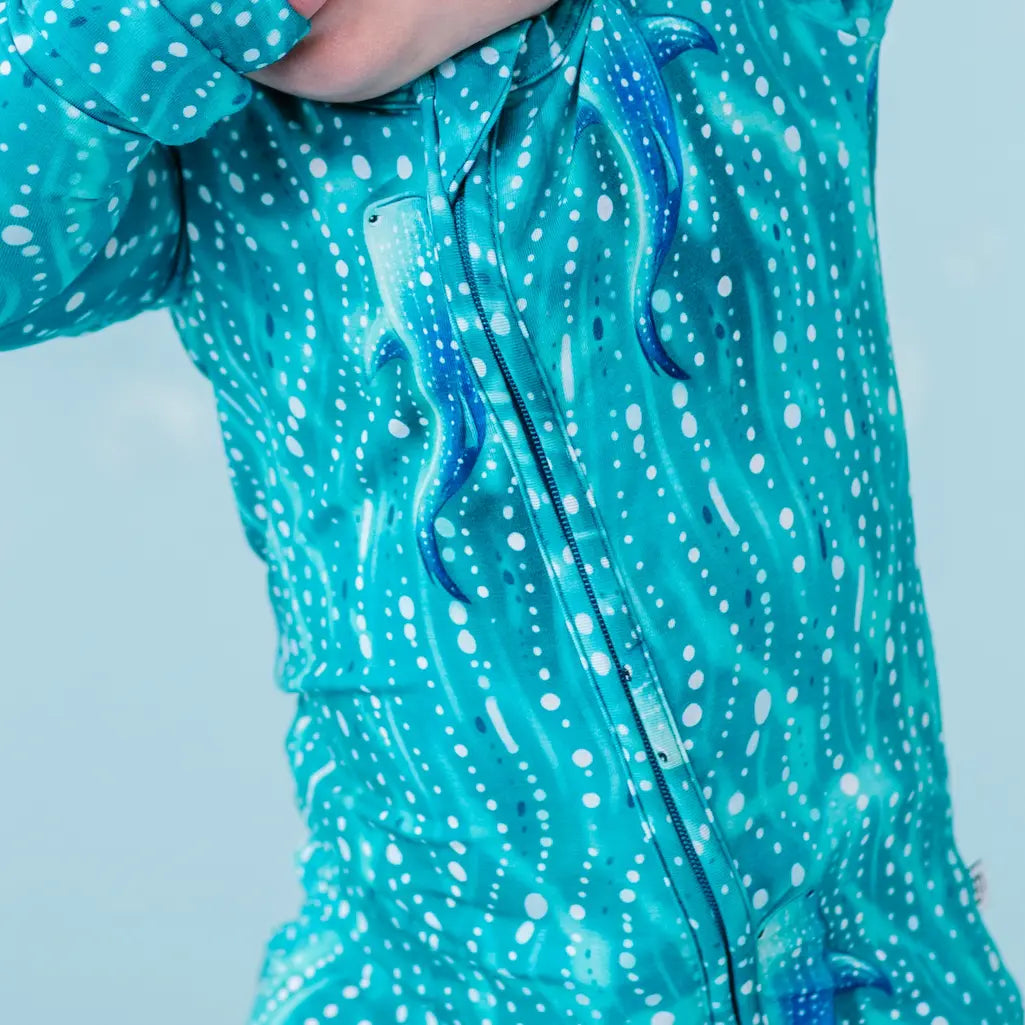 Close-up of a teal raincoat with white polka dot pattern on a light blue background