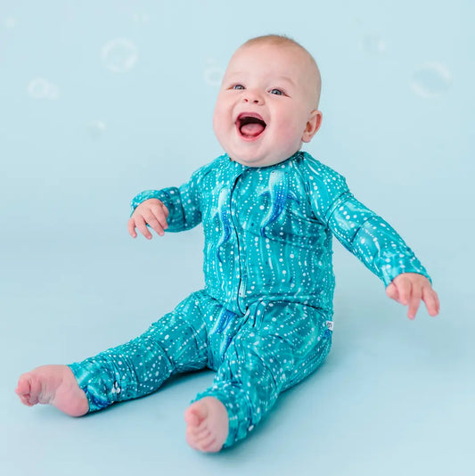 Baby in teal patterned outfit on a light blue background