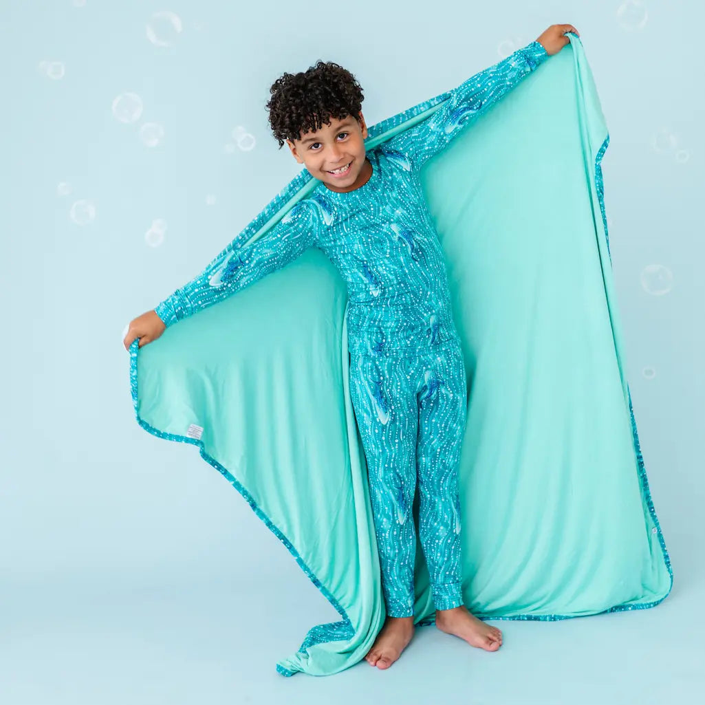 Child in a blue sequined outfit with a matching blanket on a light blue background.
