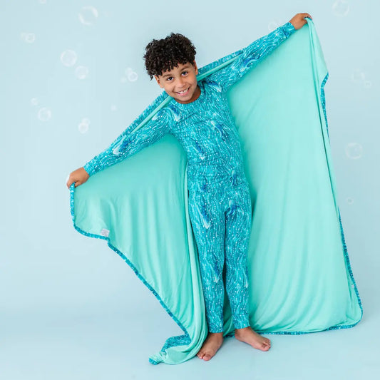 Child in a blue sequined outfit with a matching blanket on a light blue background.