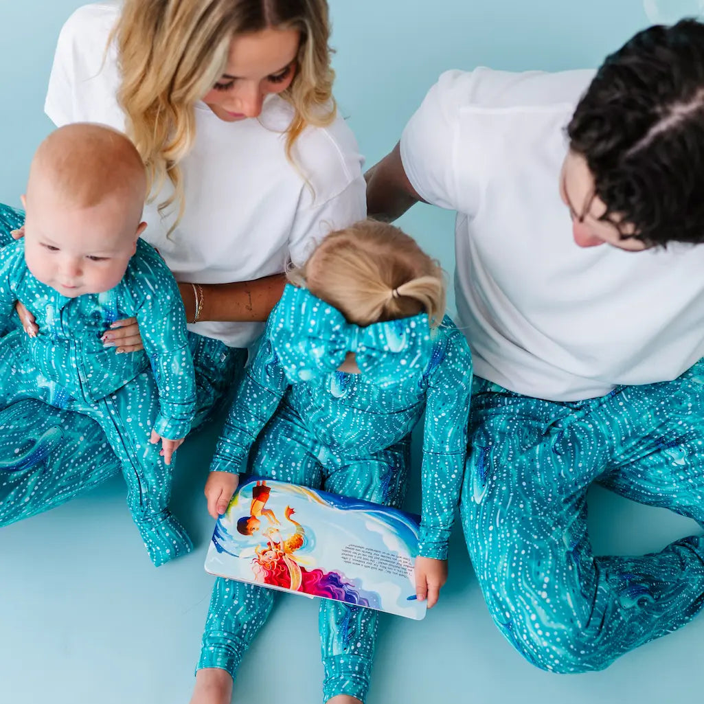 Family in matching teal outfits with a child holding a book.