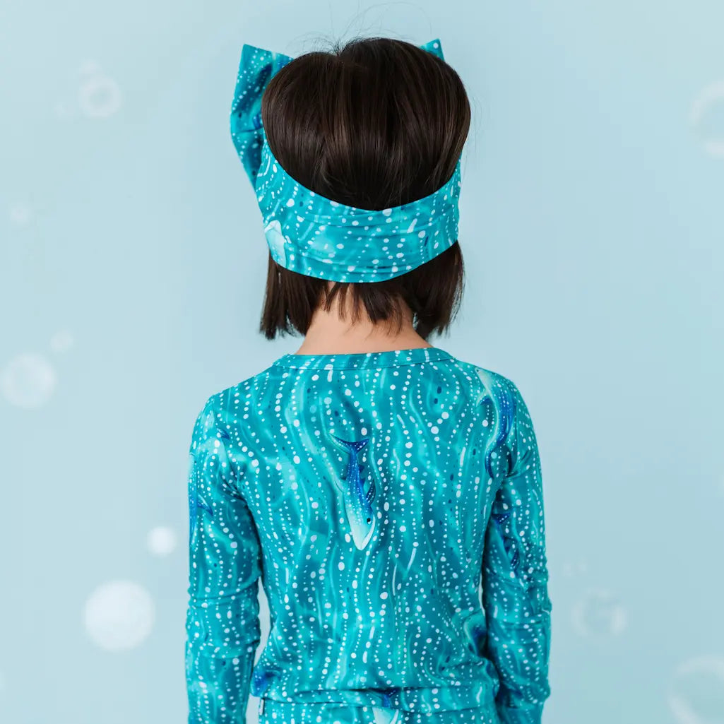 Person wearing a blue sequined outfit with a bow on their head.