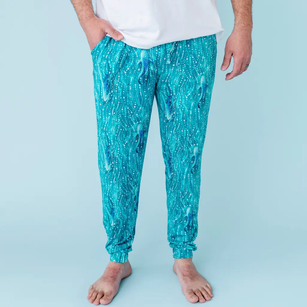 Person wearing teal jogger pants with a white background
