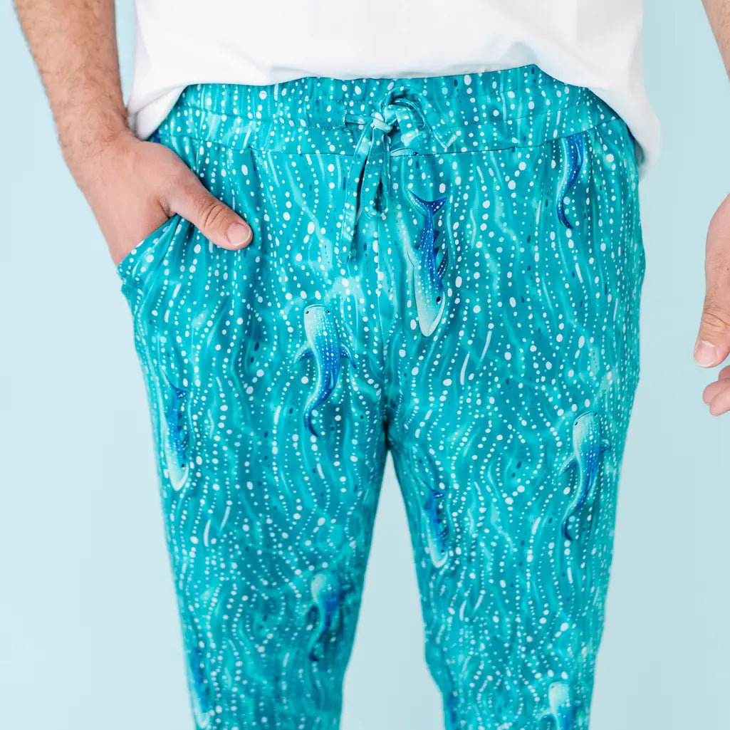 Person wearing teal whale shark patterned pants on a white background
