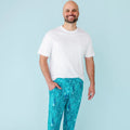 A man wearing white t-shirt and blue pajama pants with a whale shark and underwater design.