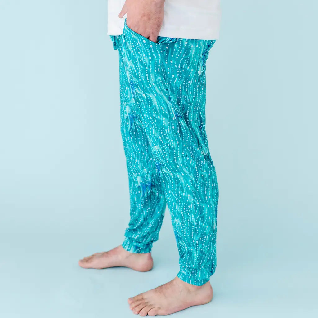 Man wearing teal whale shark patterned pajama pants on a white background