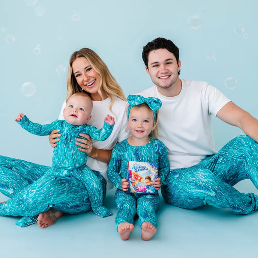 Family of four in matching teal outfits with bubbles on a light blue background.
