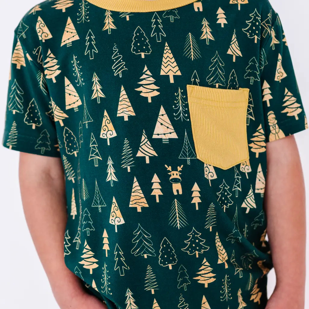 Close up of the front of a short sleeve pocket tee with a mustard ribbed collar and pocket in a dark green print of gold Christmas trees.