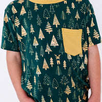 Close up of the front of a short sleeve pocket tee with a mustard ribbed collar and pocket in a dark green print of gold Christmas trees.