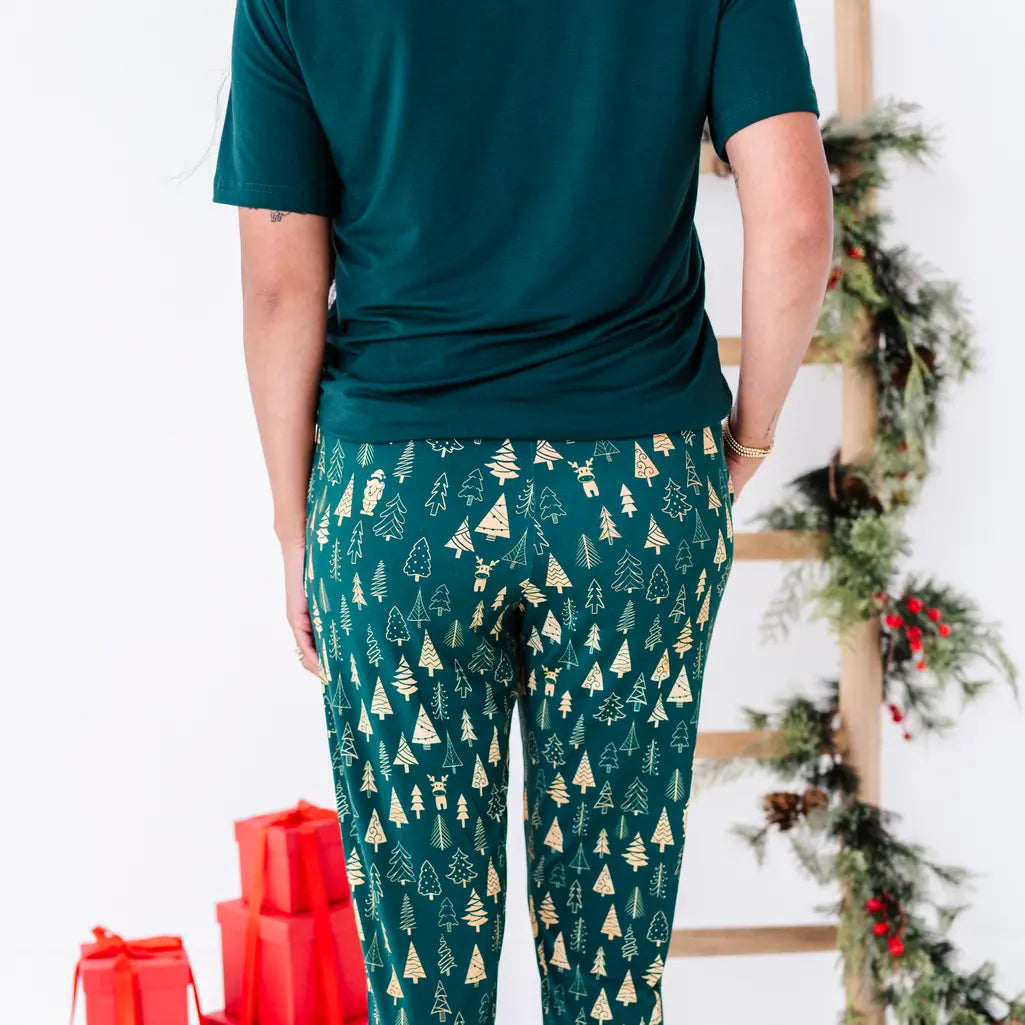 Back view of jogger pajama pants in a dark green print of gold Christmas trees, with a dark green tee.